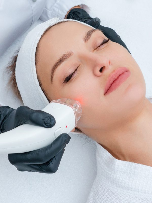 Woman-getting-a-laser-treatment-on-her-face-by-a-cosmetic-practitioner-scaled